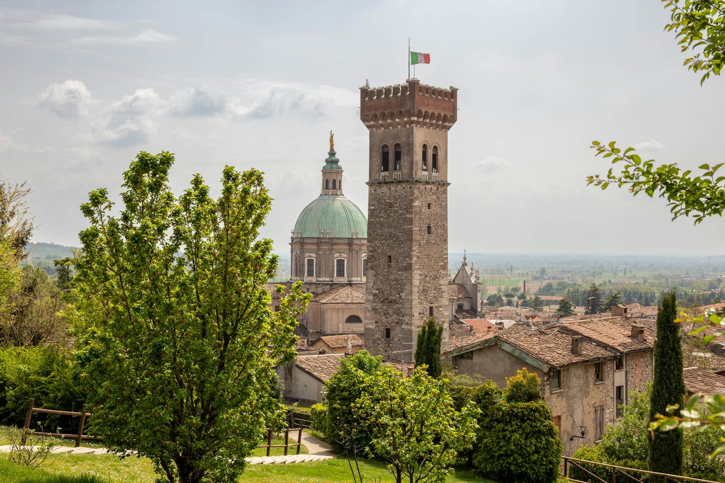 Paese italiano con torre in pietra e chiesa a cupola.