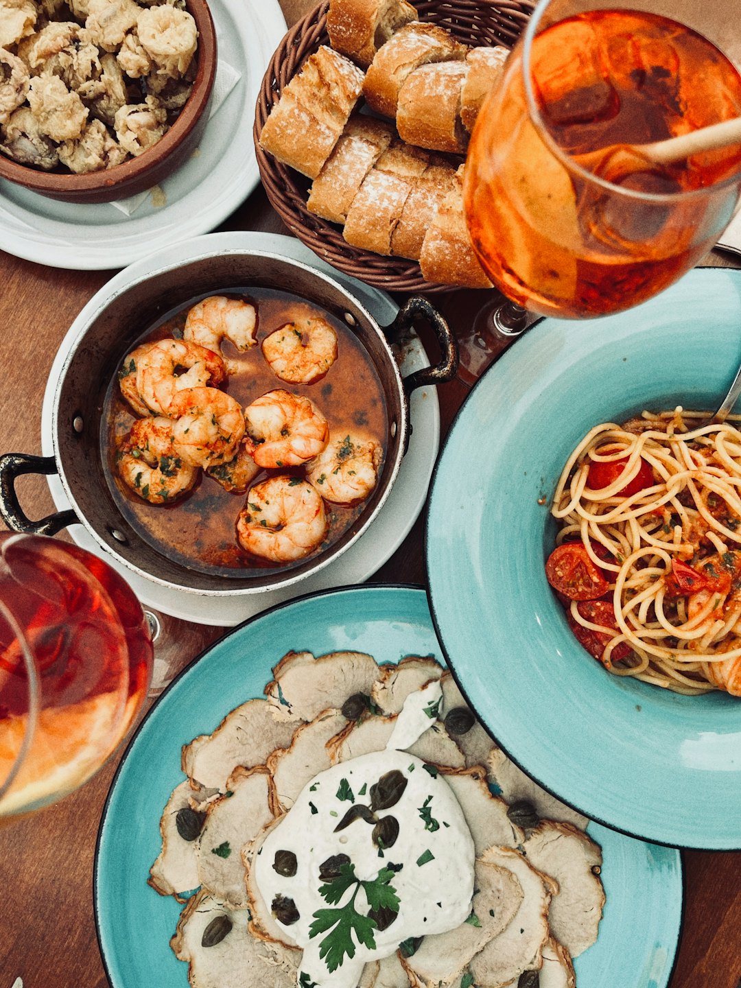 Piatti italiani e cocktail disposti su un tavolo di legno rustico.