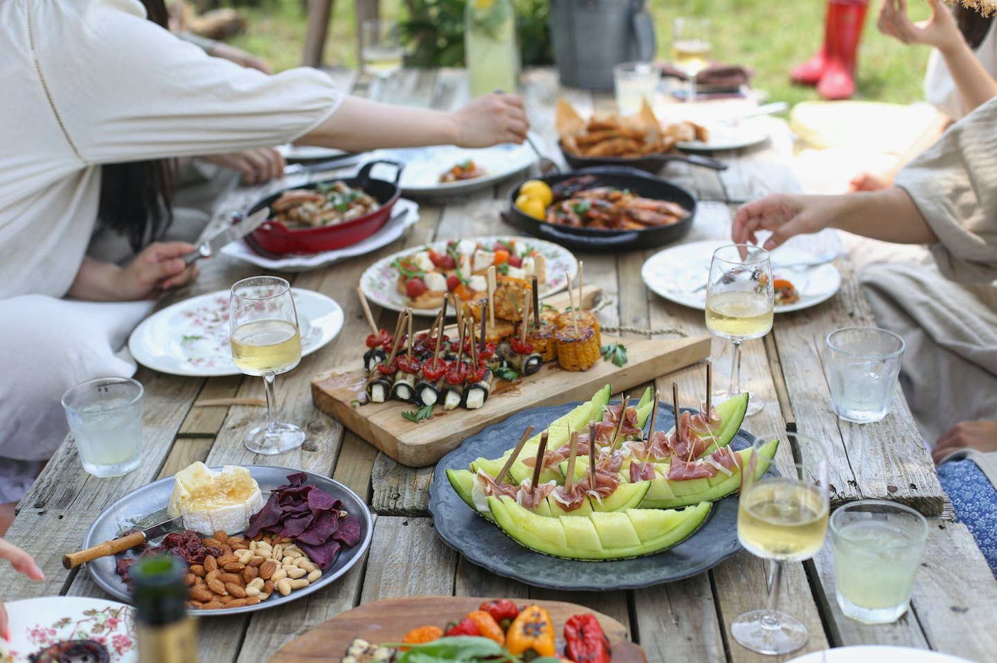 Amici condividono un pasto all'aperto a un tavolo di legno rustico.